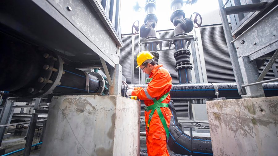 Technician working on industrial process pipework in protective gear