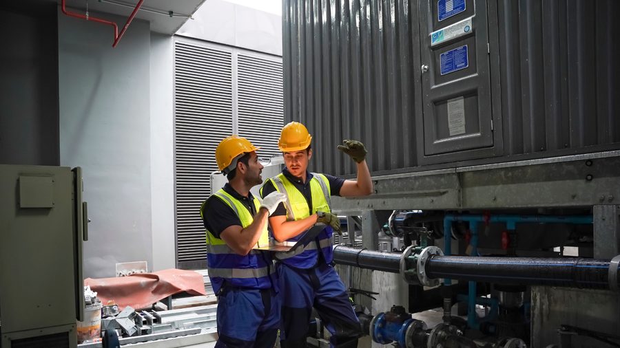 Two technicians in high-visibility gear inspecting rooftop mechanical plant